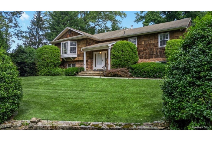 35 Pinehurst sits proudly with lush lawn and landscaping accented by stone walls lining the driveway as you approach the house.