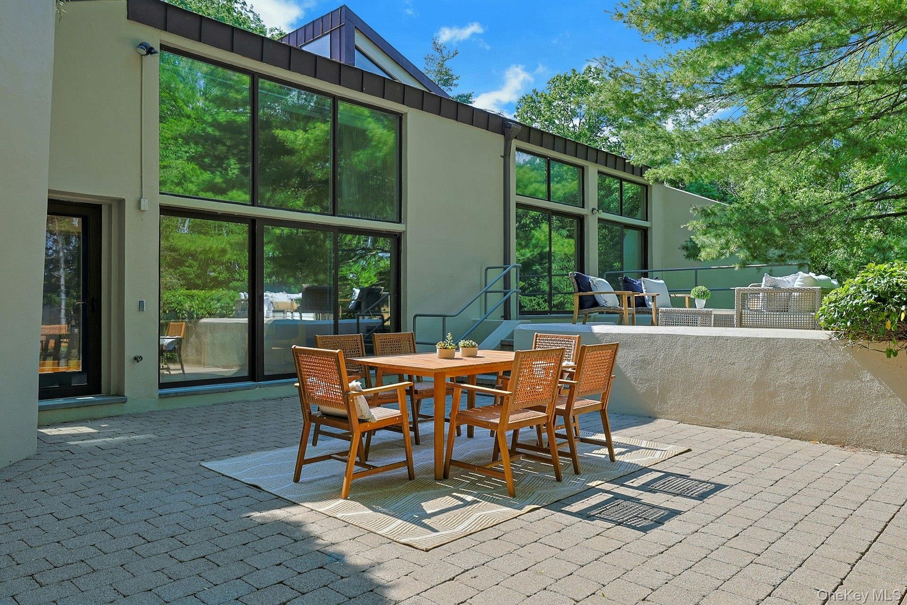 This spacious patio,  perfect for al fresco dining, blurs the line between indoors and outdoors, enhancing the home's modern design and connection to 