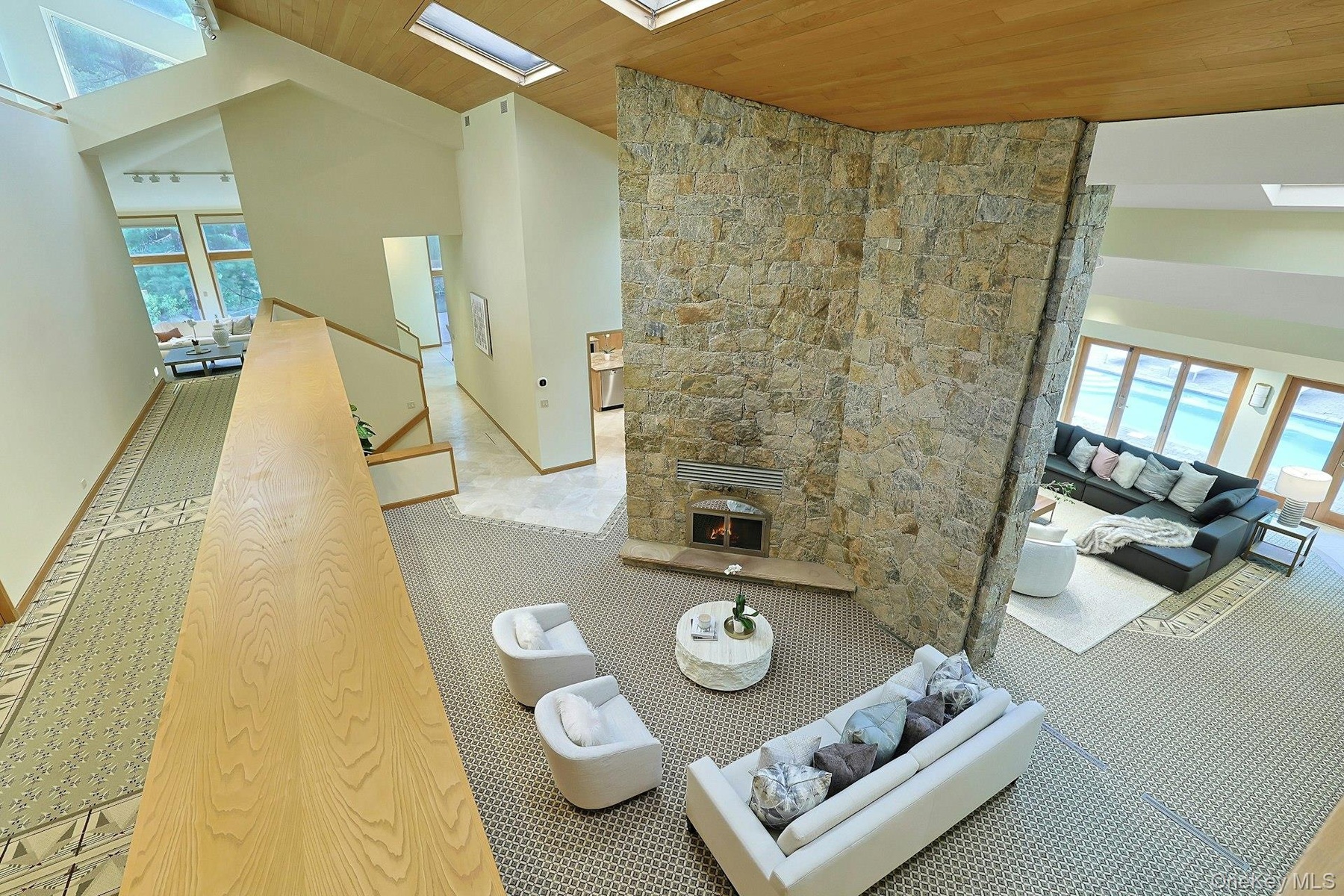 A stunning fieldstone fireplace rises dramatically through the heart of the home, anchoring multiple living areas.