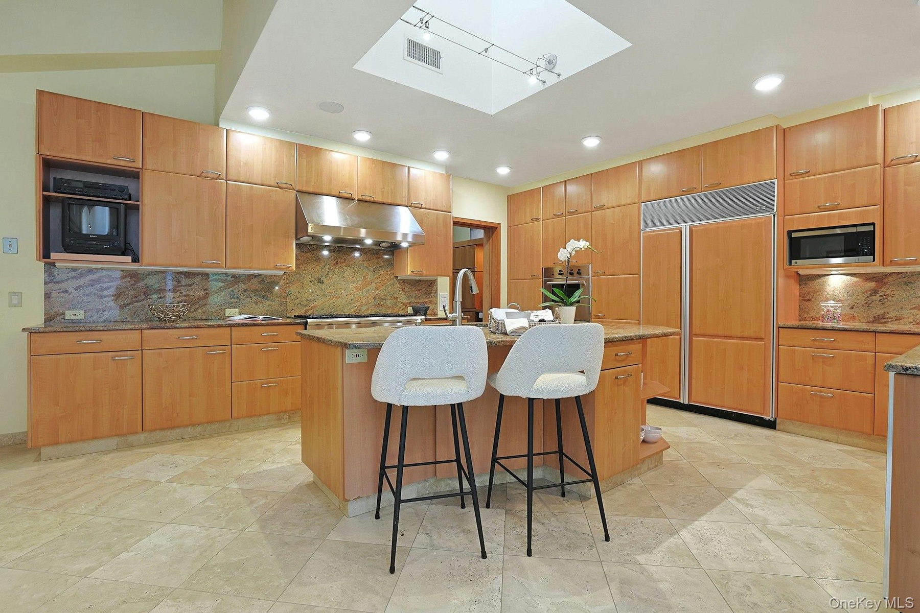 The chef's kitchen features custom oak cabinetry, granite countertops, premium appliances, and a large center island designed for gathering.