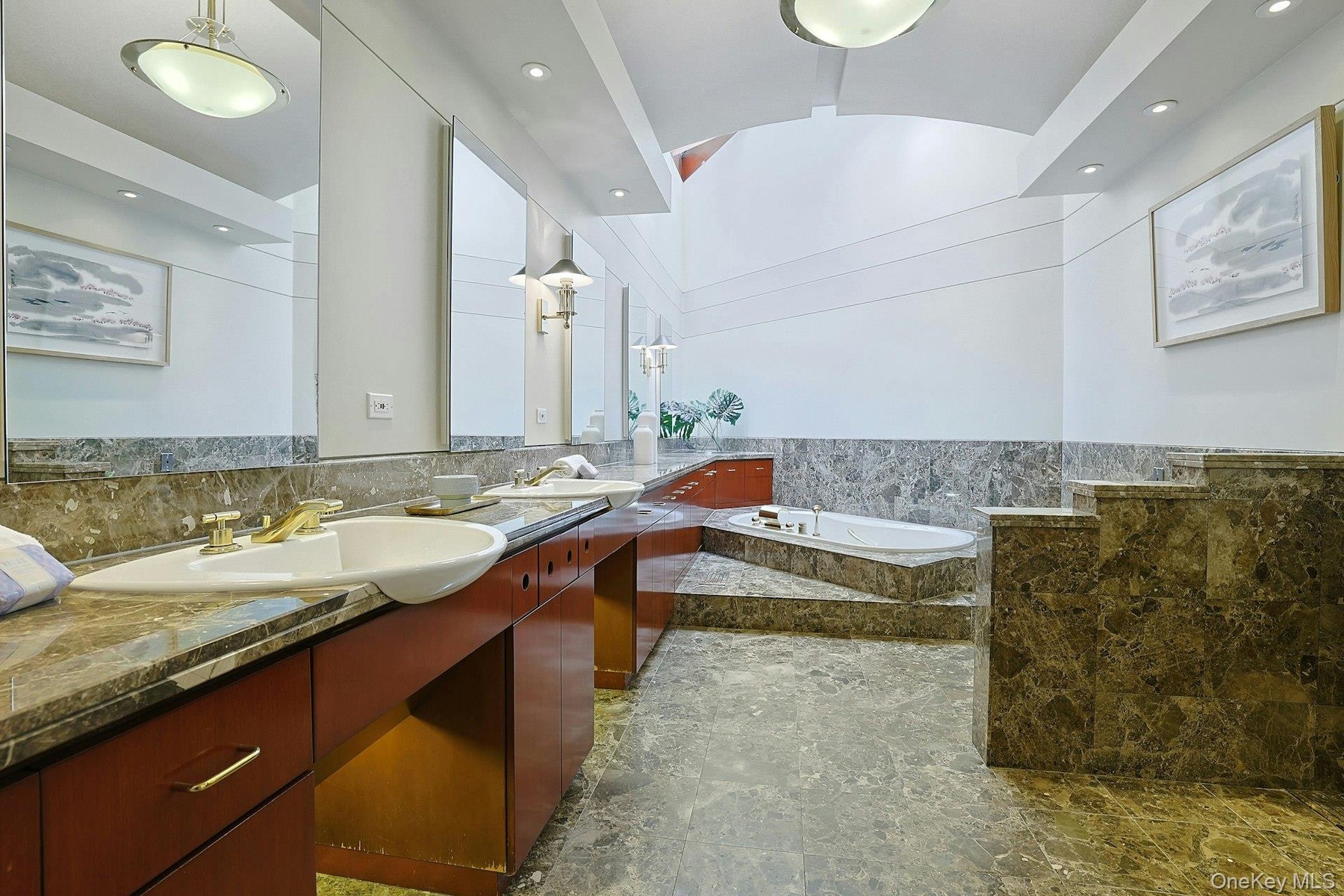 The luxurious primary bath features a skylight, oversized Jacuzzi tub, and elegant stone finishes throughout.