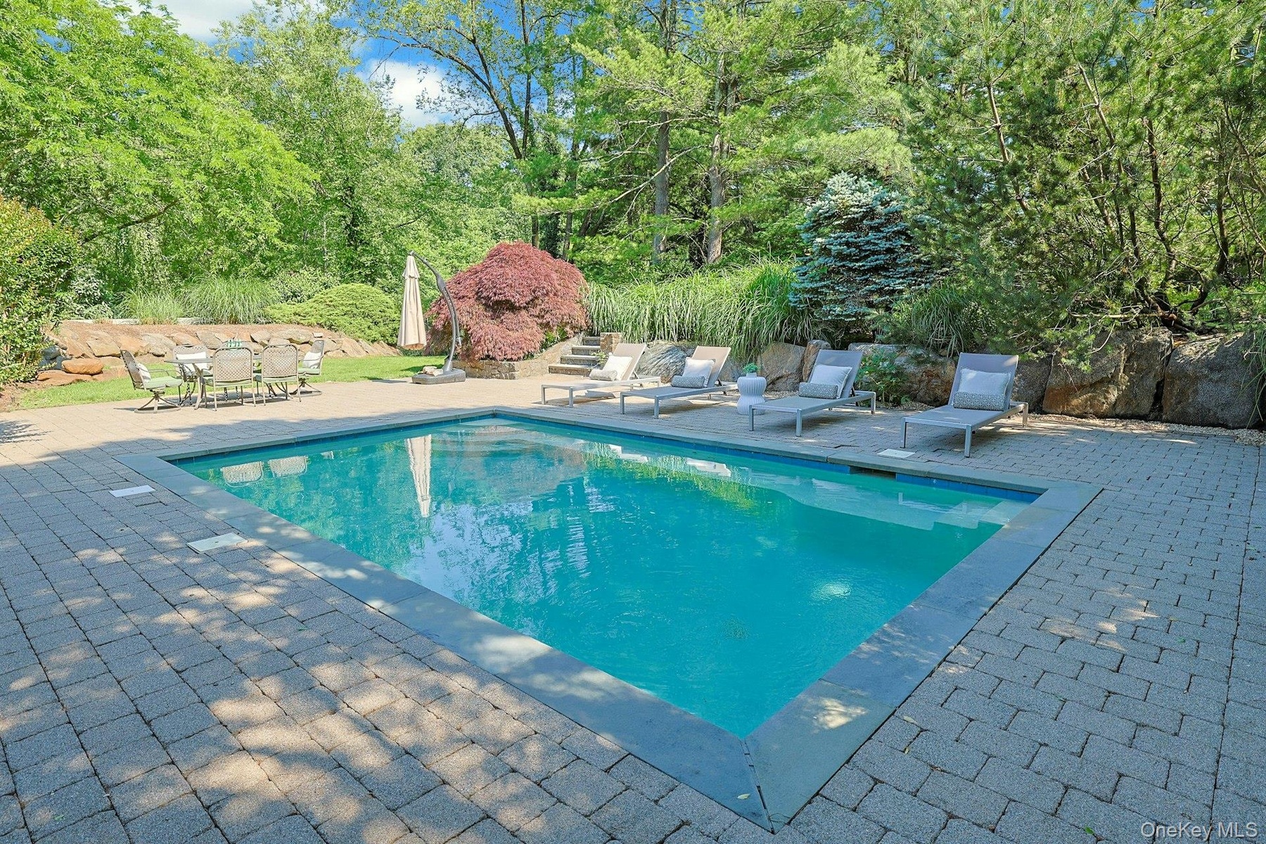 Inspired by the serenity of a Japanese garden, the pool area is surrounded by thoughtfully curated plantings, stonework, and specimen trees.