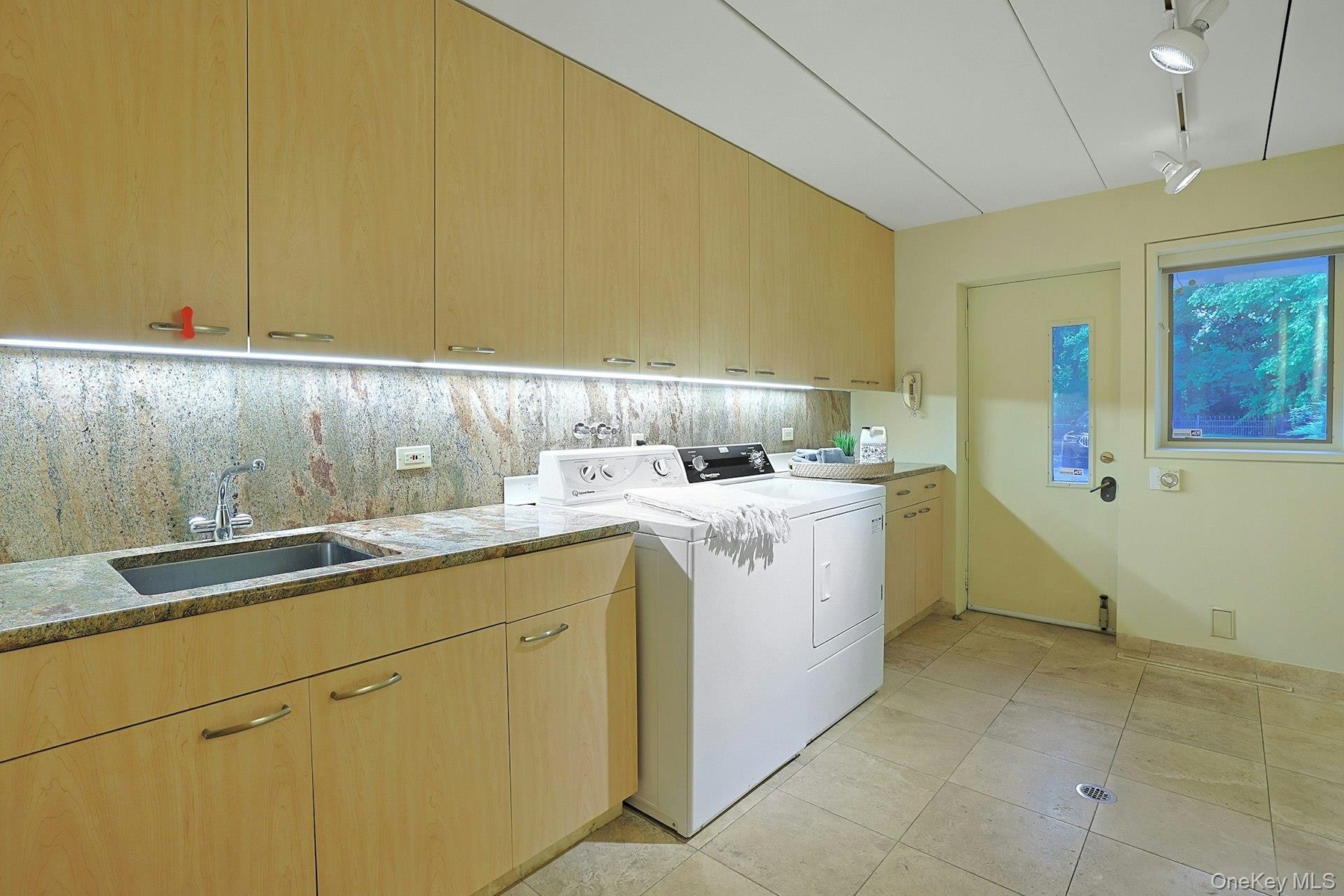 The expansive laundry and utility room provides abundant storage, workspace, and convenient access to the driveway and parking court.