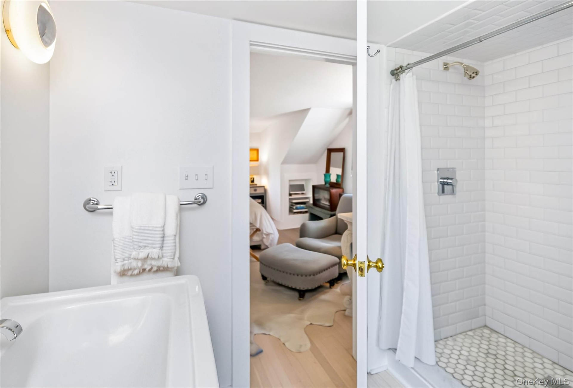 Primary bathroom featuring a white subway tile shower with hexagonal tile flooring, a white porcelain tub, and a chrome towel bar