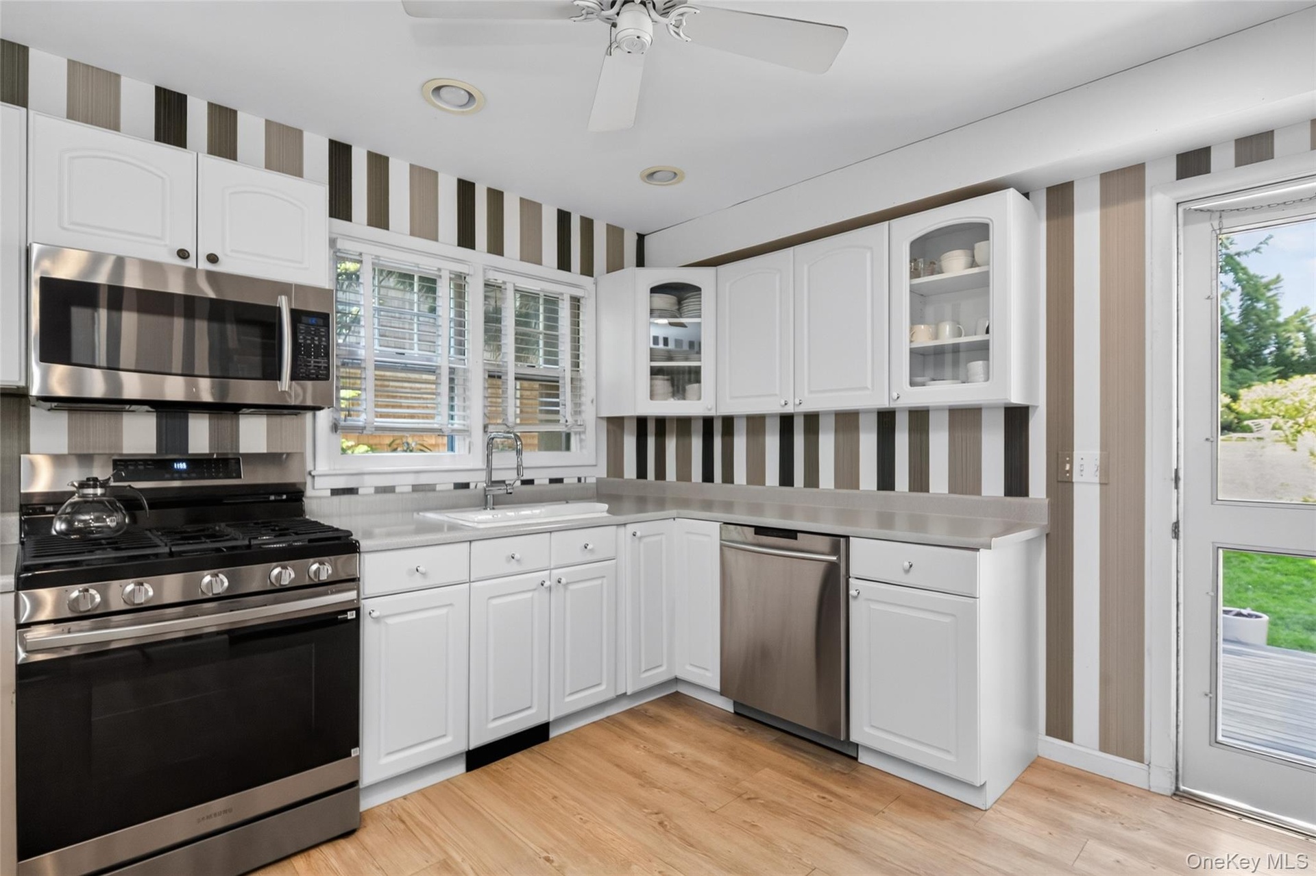 Kitchen featuring wood-finish flooring, white cabinetry, and access to the rear dining pavilion