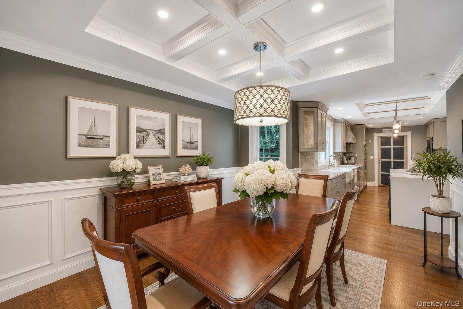 Dining area featuring coffered ceilings with recessed lighting, wood-finish flooring, and wainscoting