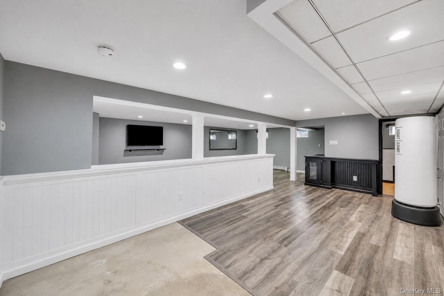 Spacious lower level featuring wood-finish flooring, recessed lighting, and a built-in wet bar with a beverage refrigerator