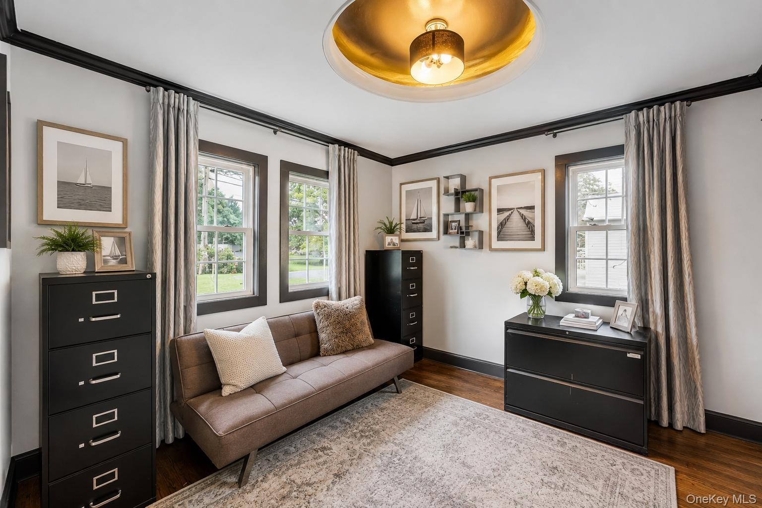 Interior space featuring dark wood-finish flooring, light grey walls with contrasting dark trim, and multiple windows providing natural illumination