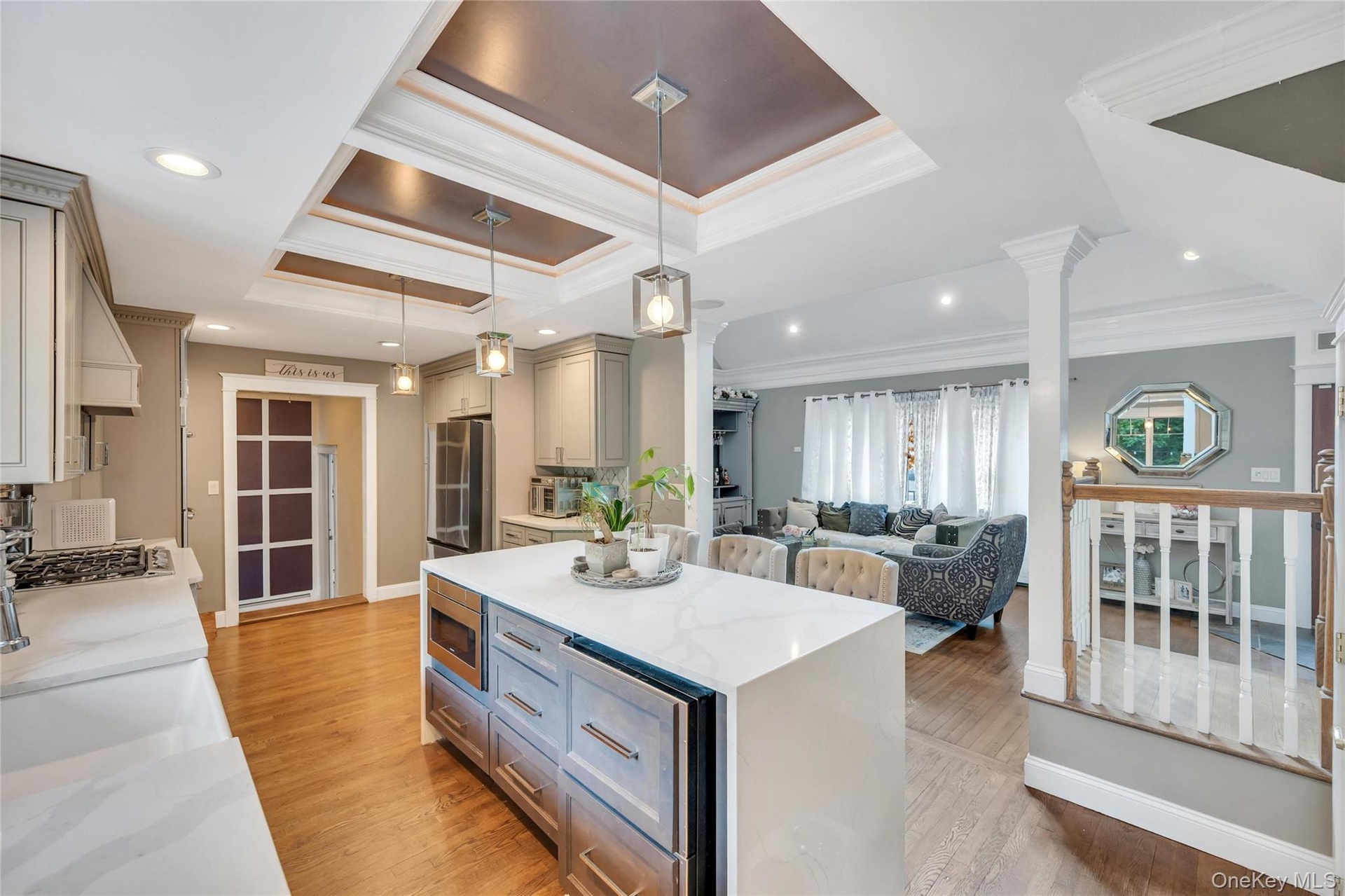 Spacious open-concept kitchen featuring light-toned cabinetry, a waterfall-edge island with an integrated microwave, quartz countertops, and recessed 