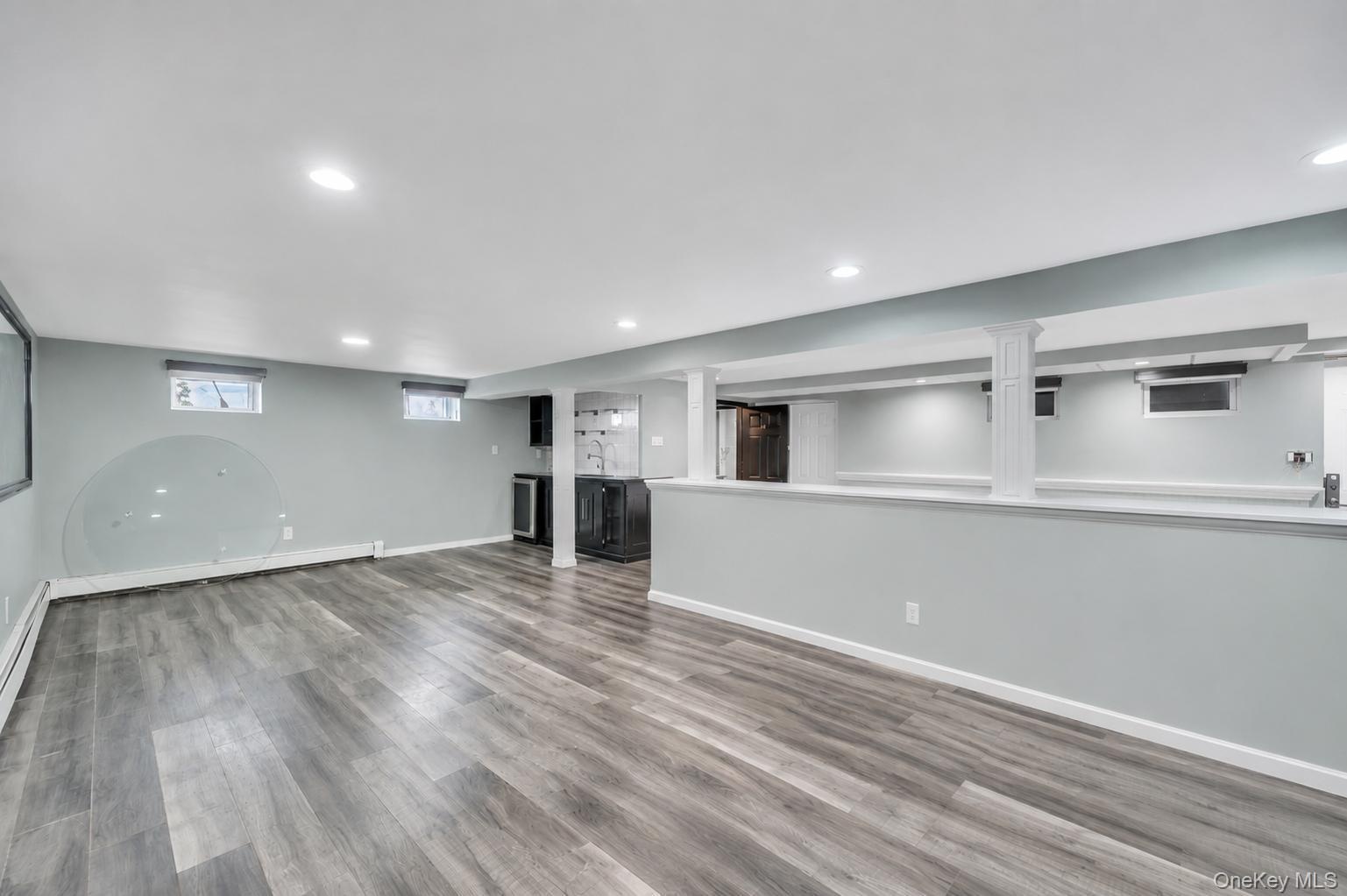 Spacious lower level featuring wood-finish flooring, recessed lighting, and a built-in wet bar with a beverage refrigerator