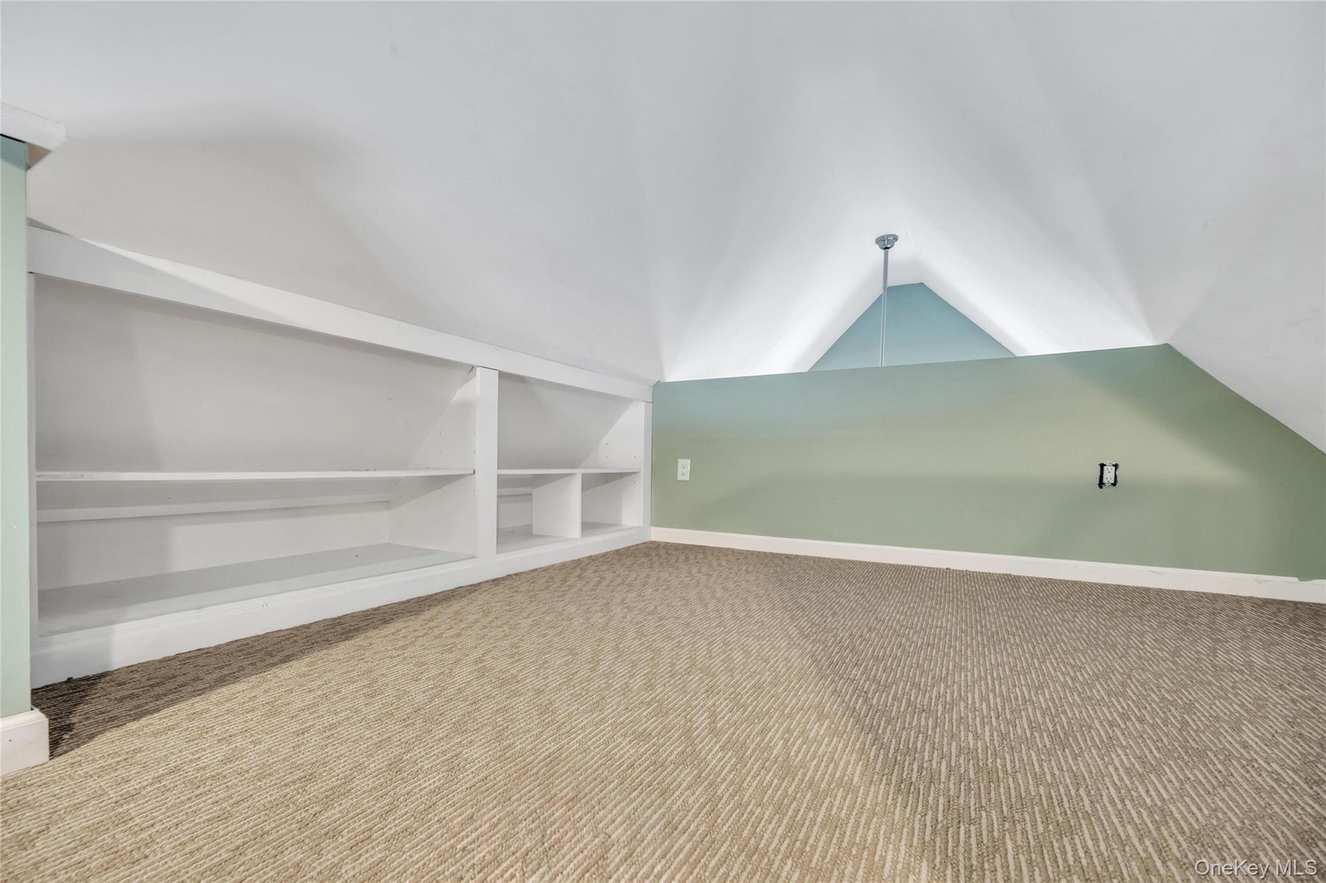 Vaulted ceiling with a recessed light fixture, built-in shelving, low-pile patterned carpeting, and painted accent walls