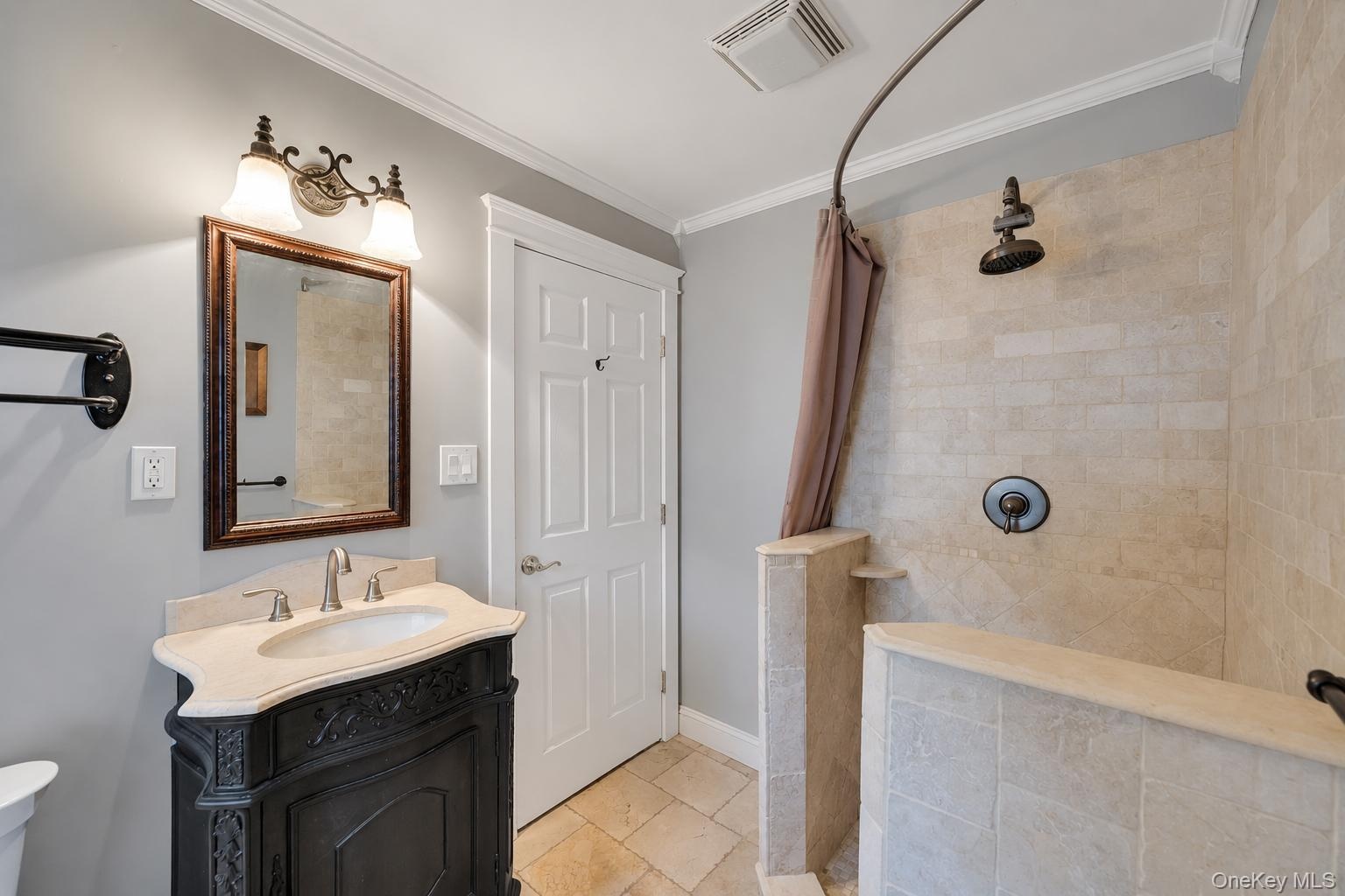 Walk-in shower with tiled walls and floor, featuring a dark bronze rainfall showerhead and control
