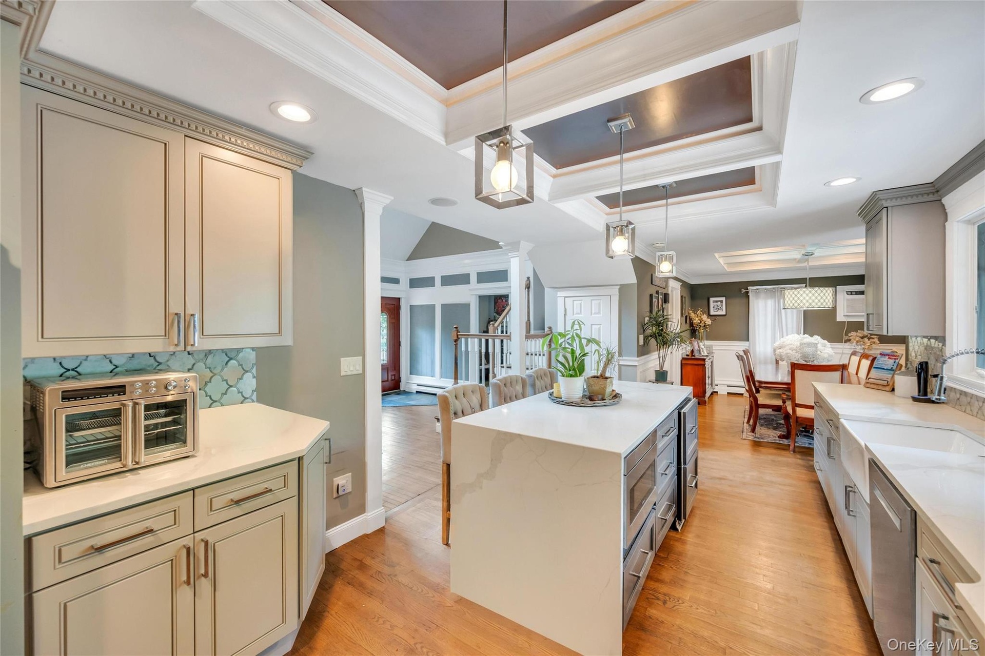 Kitchen featuring an oversized island with waterfall countertop, recessed lighting, and tray ceiling