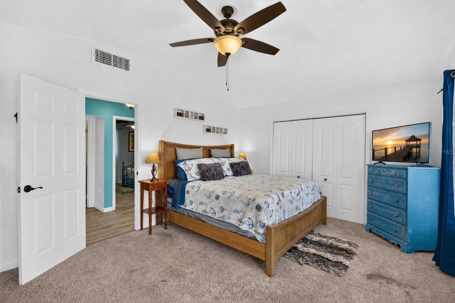 Primary bedroom featuring vaulted ceilings and coastal décor.