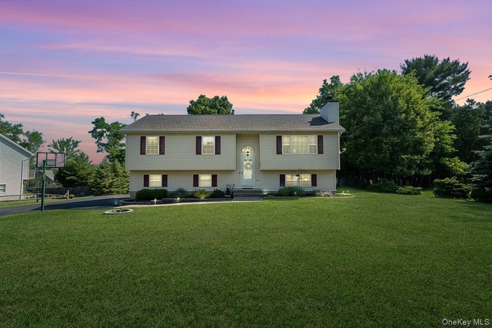 Bi-level residence featuring a light-toned exterior with dark shutters and a central entry