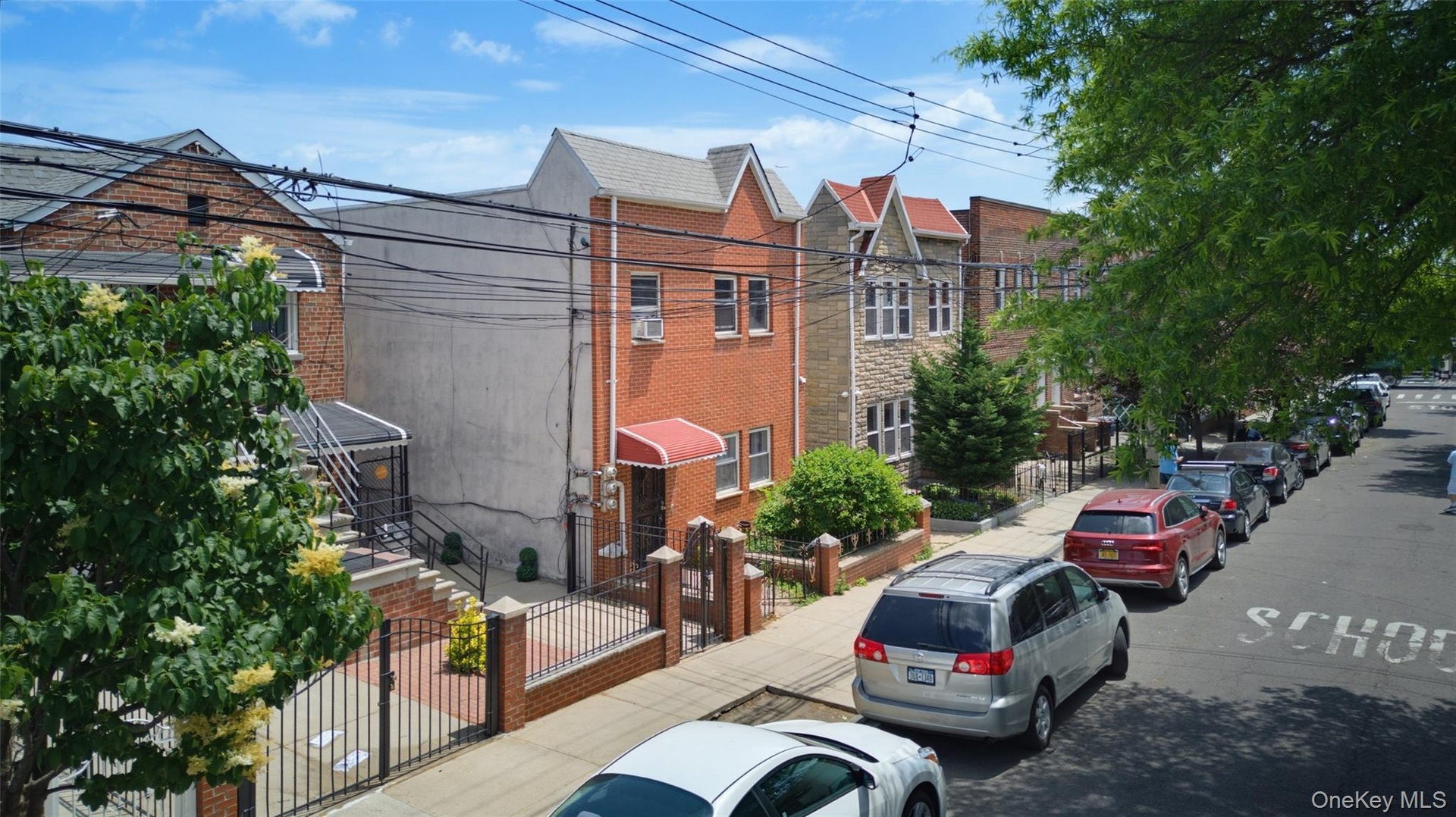 Brick facade residence with a red awning, front entry gate, and steps leading to the main entrance