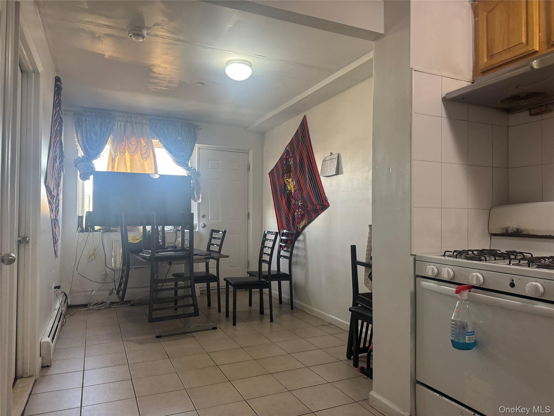 Dining room featuring light tile patterned flooring and a baseboard heating unit