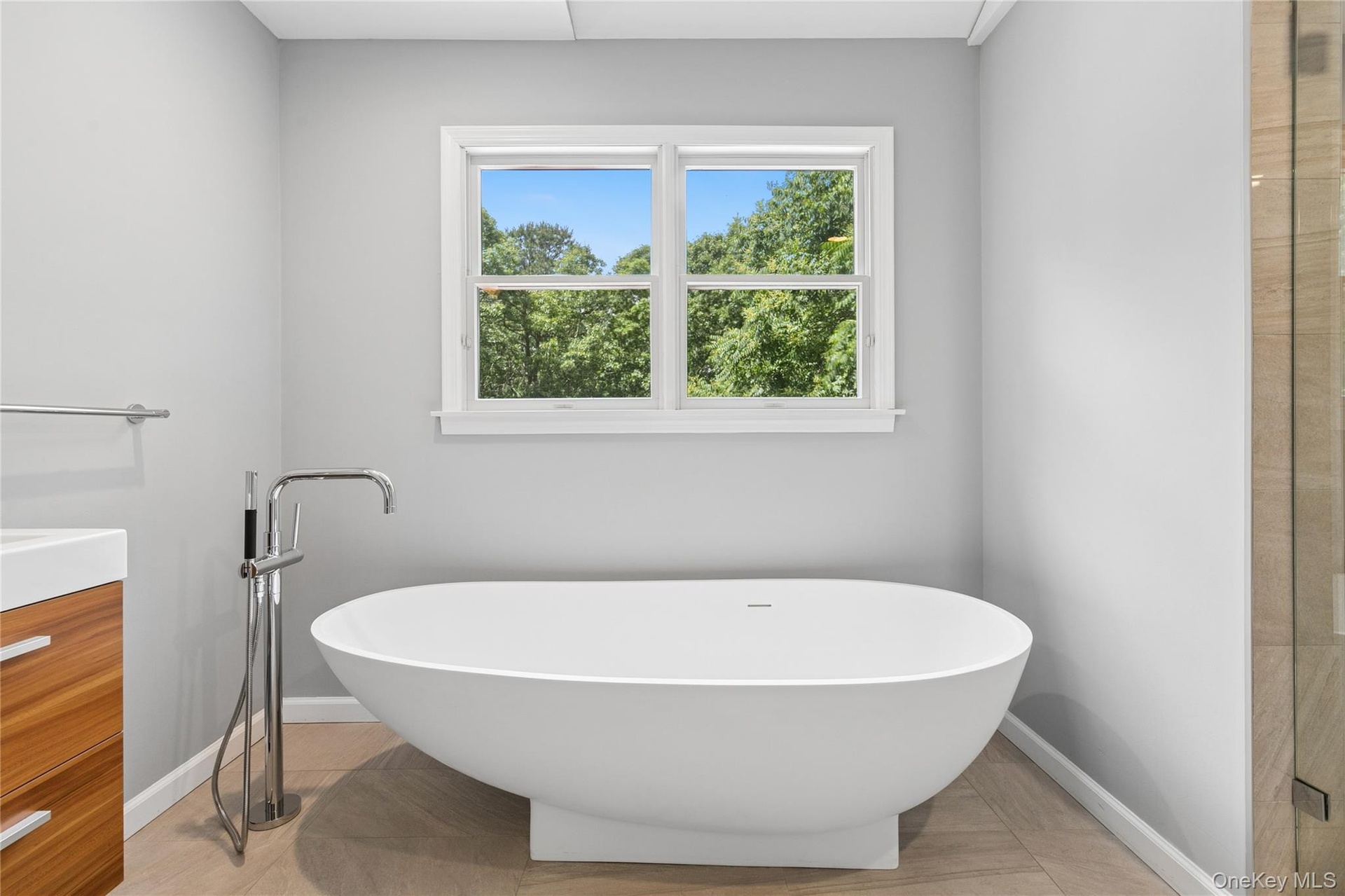 Freestanding soaking tub with a floor-mounted chrome filler