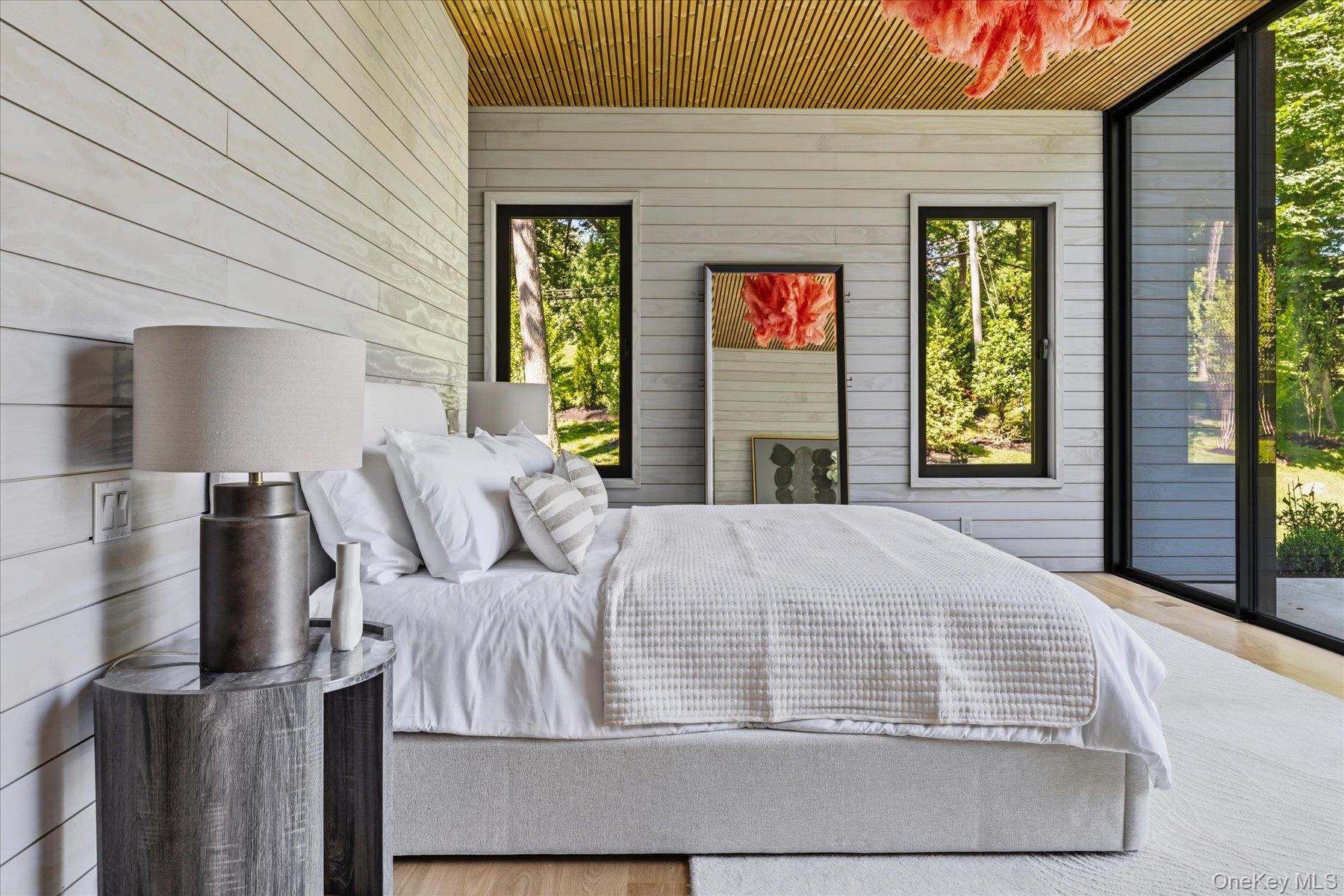 First floor primary bedroom with floor to ceiling windows, access to outdoor terrace, large walk-in closet and en suite bath