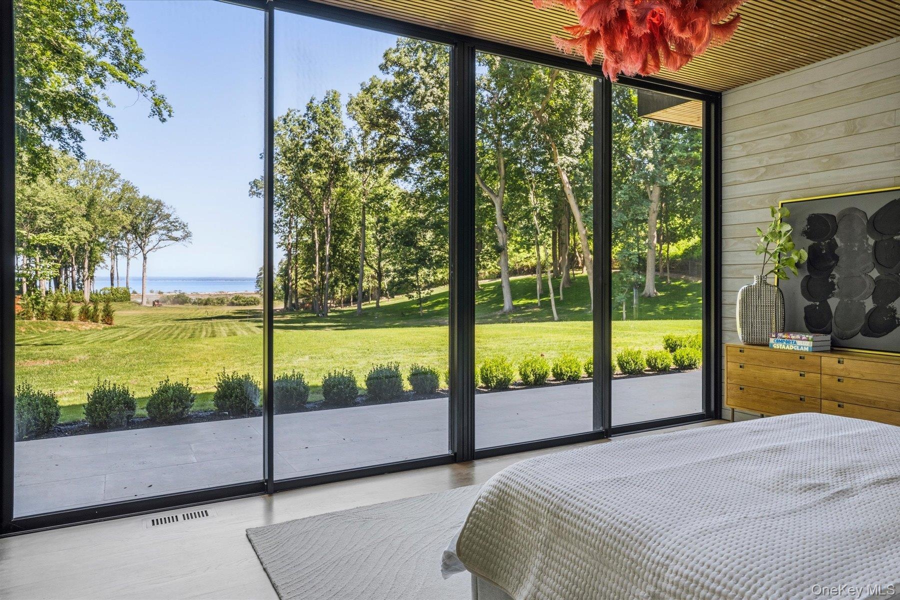 First floor primary bedroom with floor to ceiling windows, access to outdoor terrace, large walk-in closet and en suite bath.