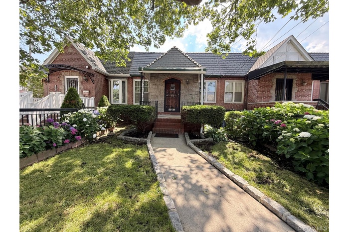Brick residence featuring a manicured law, a front porch