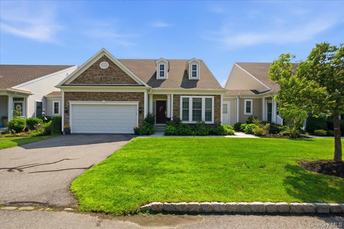 Ranch-style residence featuring a prominent stone facade, an attached two-car garage, and a gabled roofline with dormer windows