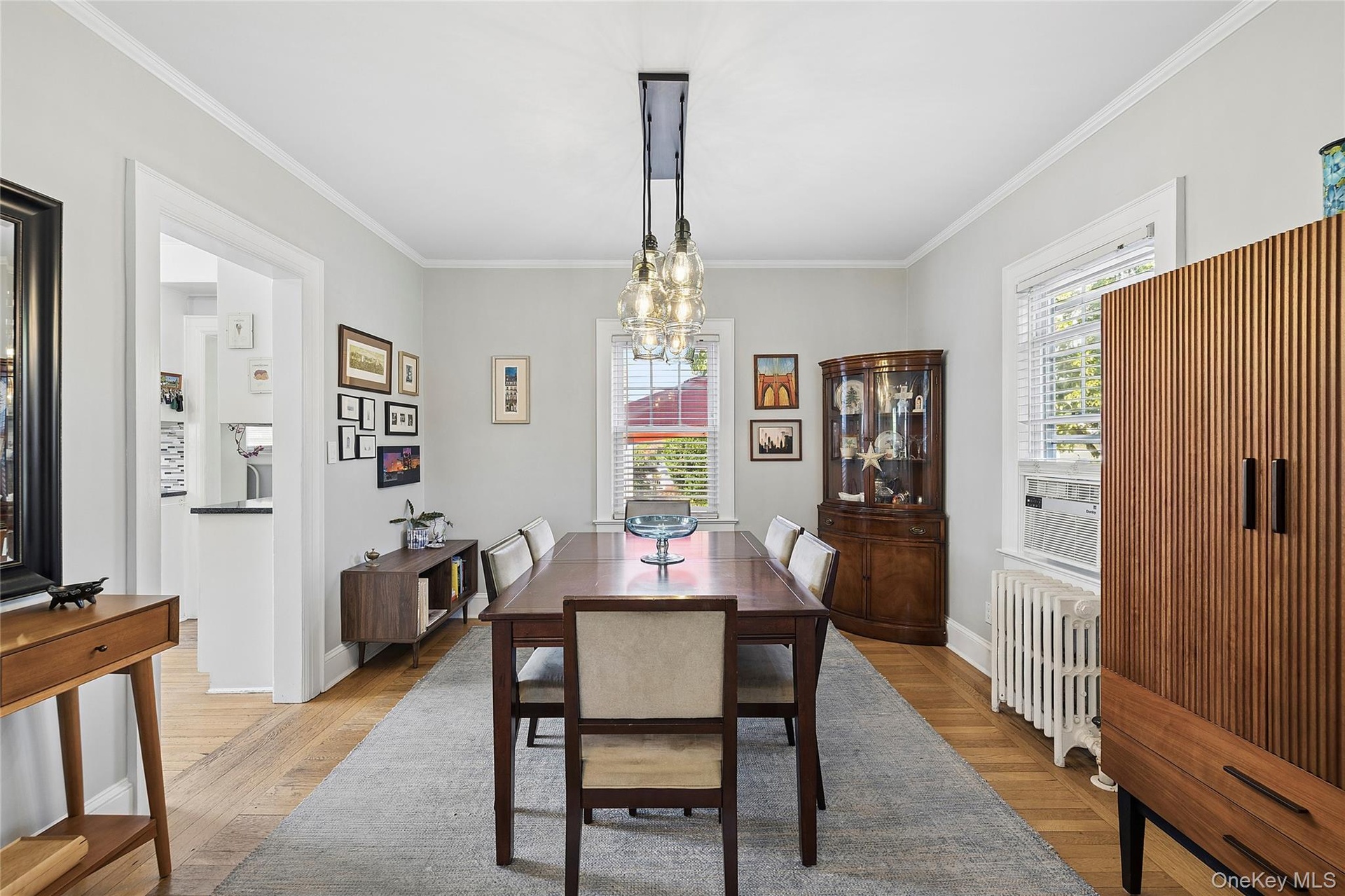Dining area featuring wood-finish flooring, light gray wall paint, and white crown molding