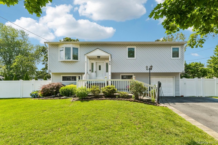 Split-level residence featuring light gray siding, a prominent bay window, and a covered entry porch