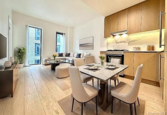 Open-concept living space featuring wood-finish flooring, a contemporary kitchen with wood cabinetry and stone backsplash, and floor-to-ceiling window