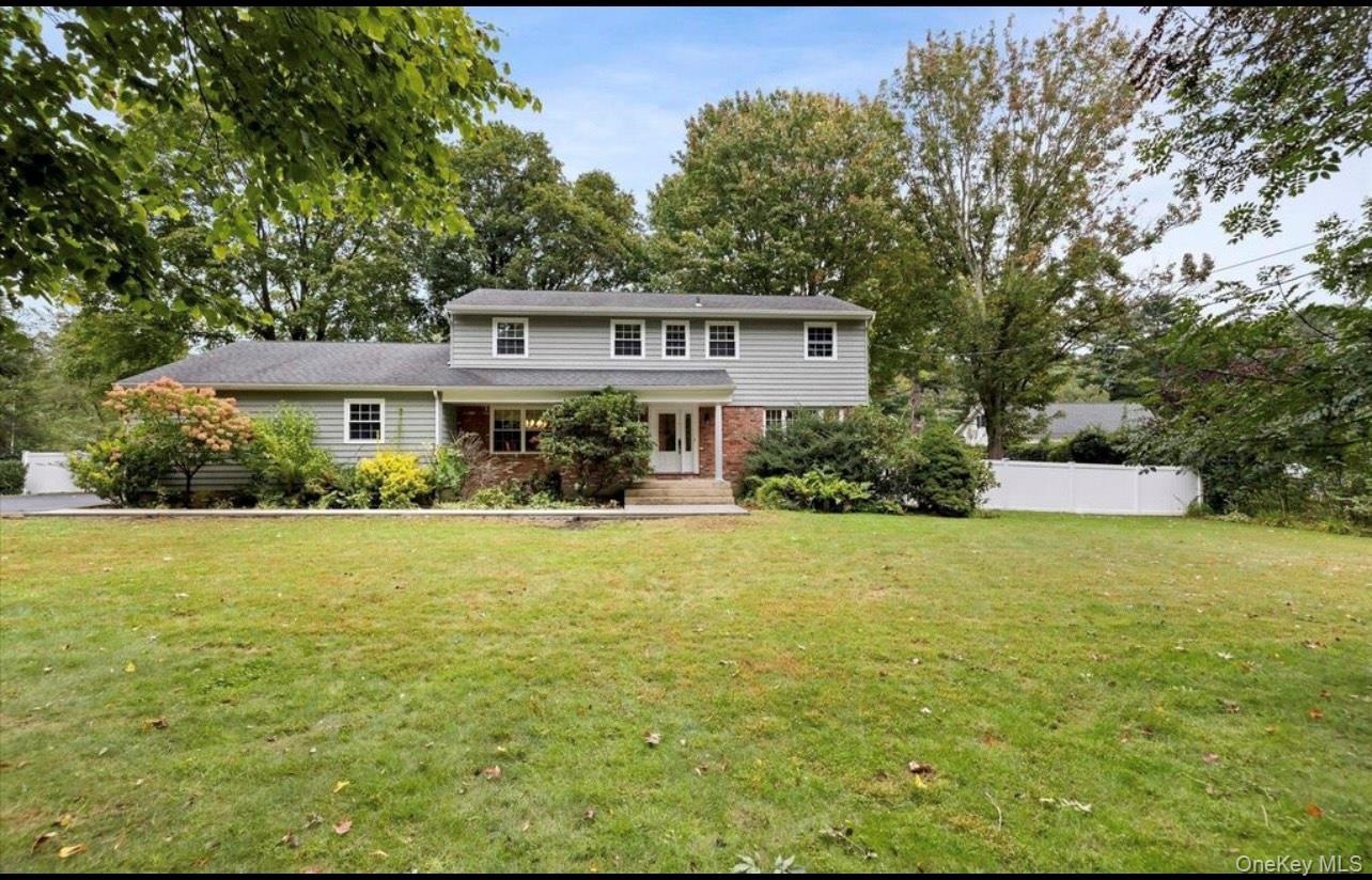 Traditional-style home with brick siding and view of scattered trees