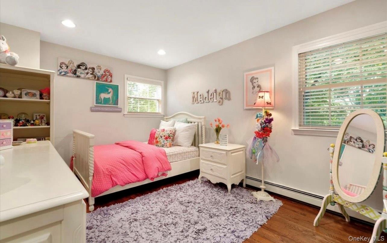 Bedroom featuring wood finished floors, a baseboard heating unit, and recessed lighting
