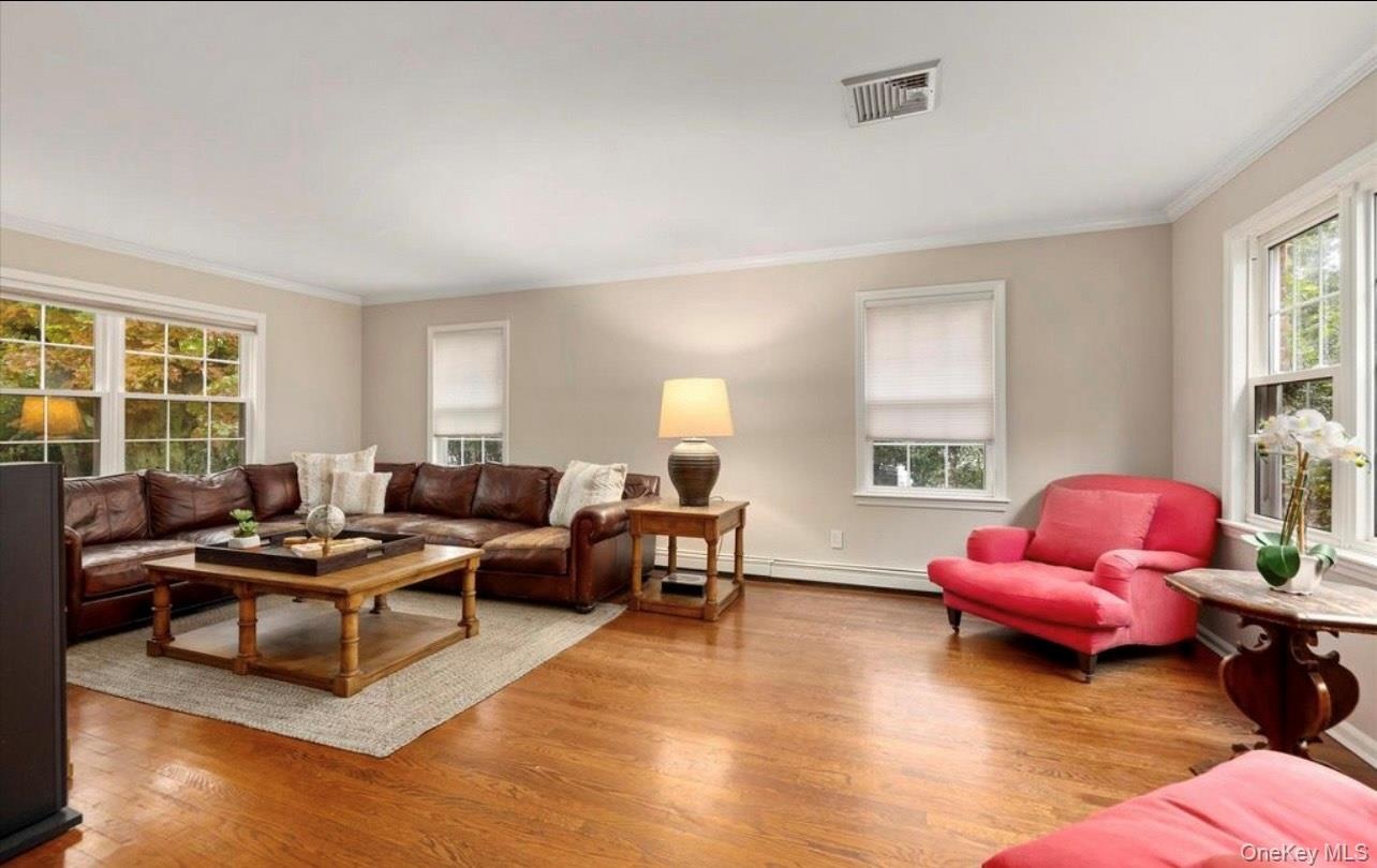 Living room featuring crown molding, wood finished floors, and a baseboard heating unit