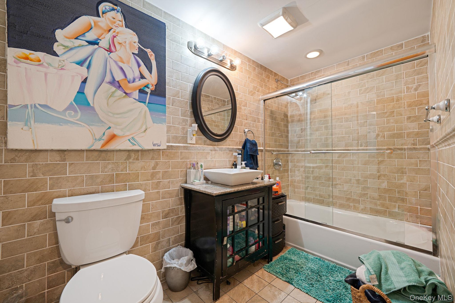 Bathroom with tile walls, shower / bath combination with glass door, vanity, tile patterned floors, and recessed lighting