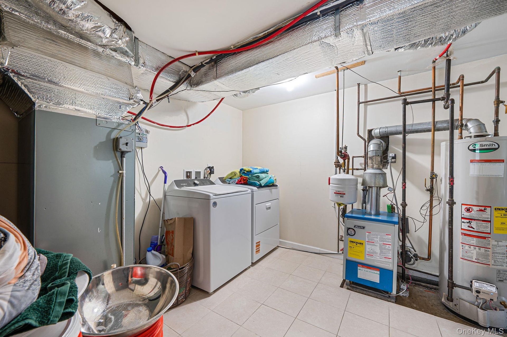 Washroom featuring water heater, washing machine and dryer, light tile patterned flooring, heating unit, and a heating unit