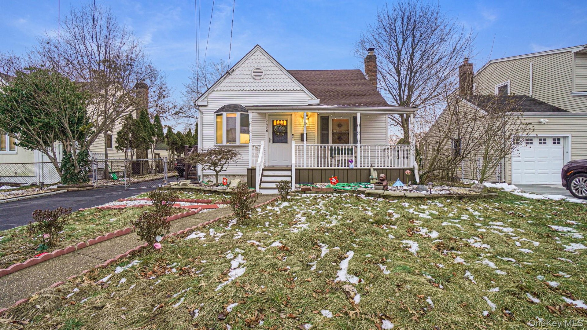 View of front of house featuring a front lawn, a chimney, covered porch, fence, and a shingled roof