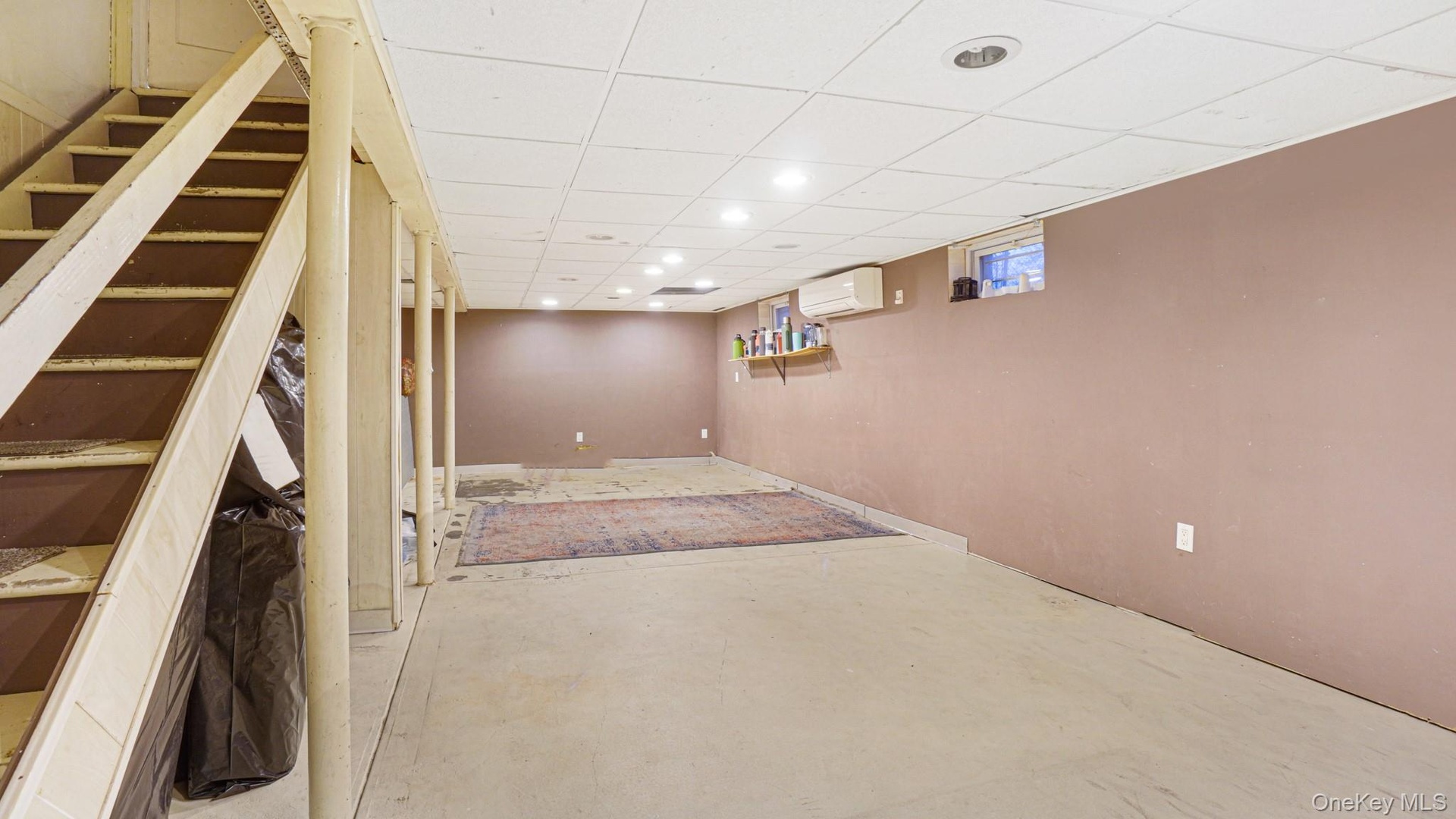 Basement with recessed lighting, a wall mounted AC, and stairway