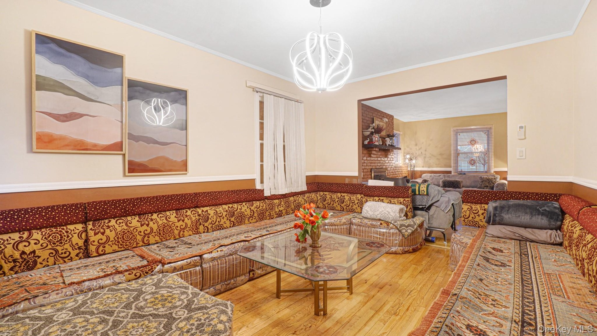 Living room with wood-type flooring, crown molding, a wainscoted wall, and a chandelier