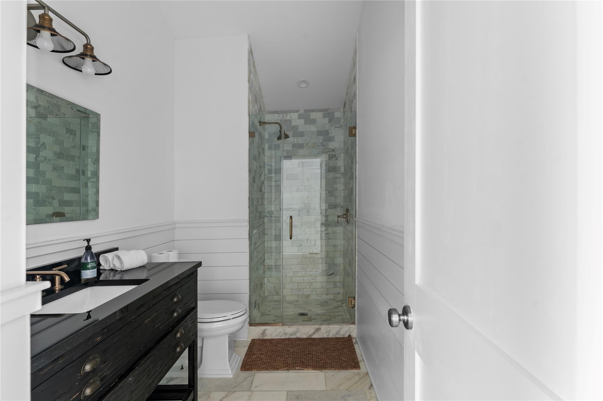Bathroom featuring vanity, toilet, and a shower with door
