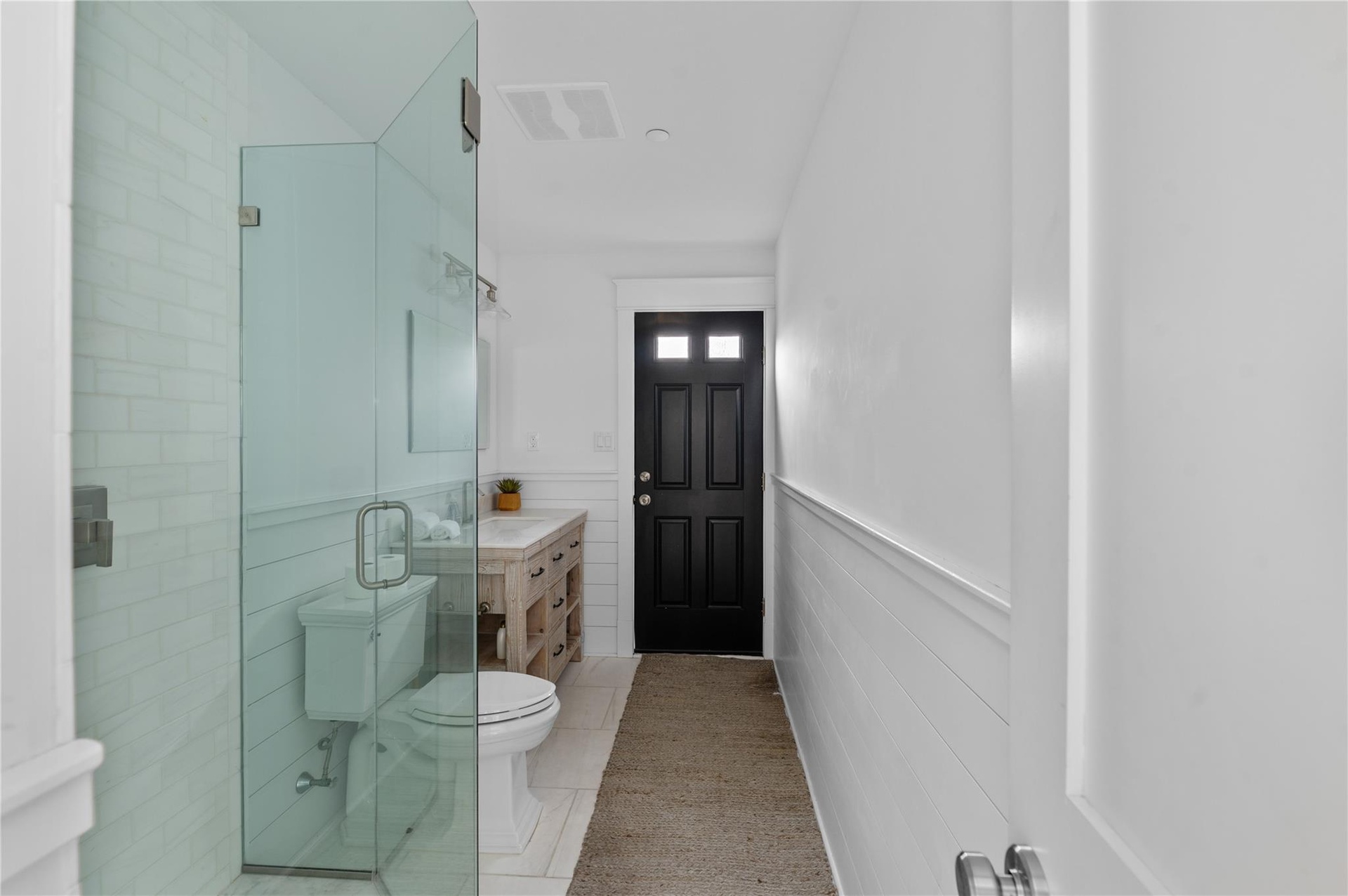 Bathroom with an enclosed shower, vanity, tile patterned floors, and toilet