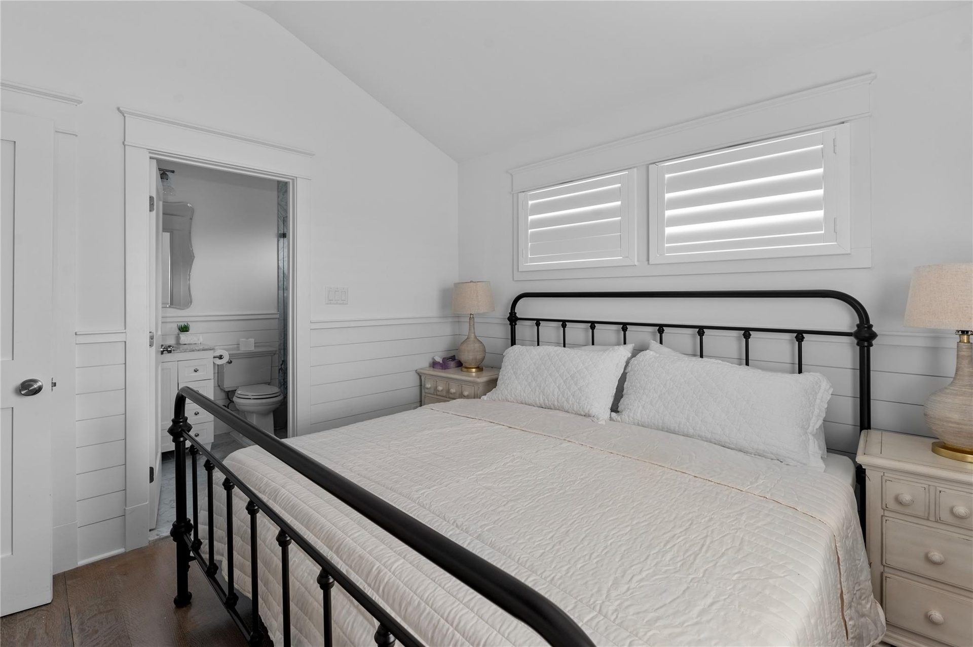 Bedroom featuring vaulted ceiling, dark hardwood / wood-style floors, and ensuite bath