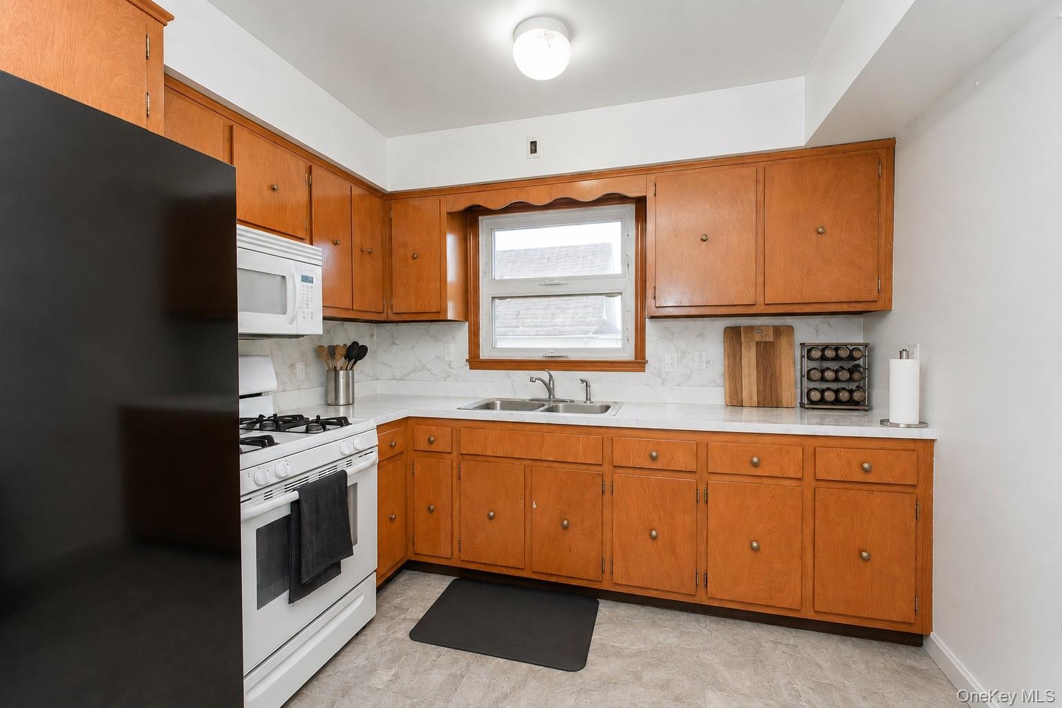 Kitchen featuring wood-finish cabinetry, white countertops, and a white tile backsplash