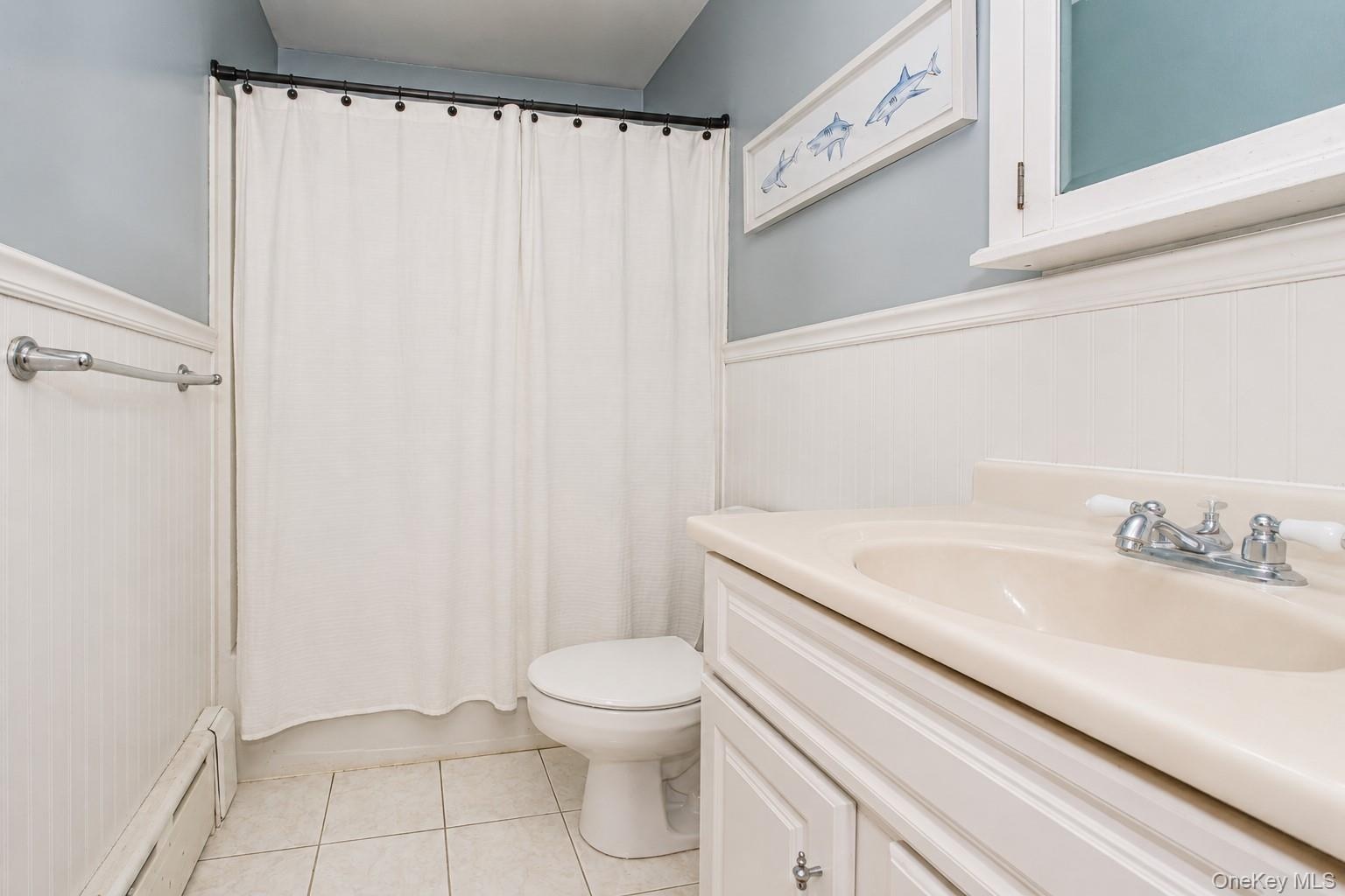 Bathroom featuring a white vanity with integrated sink, chrome faucet, and white paneled wainscoting