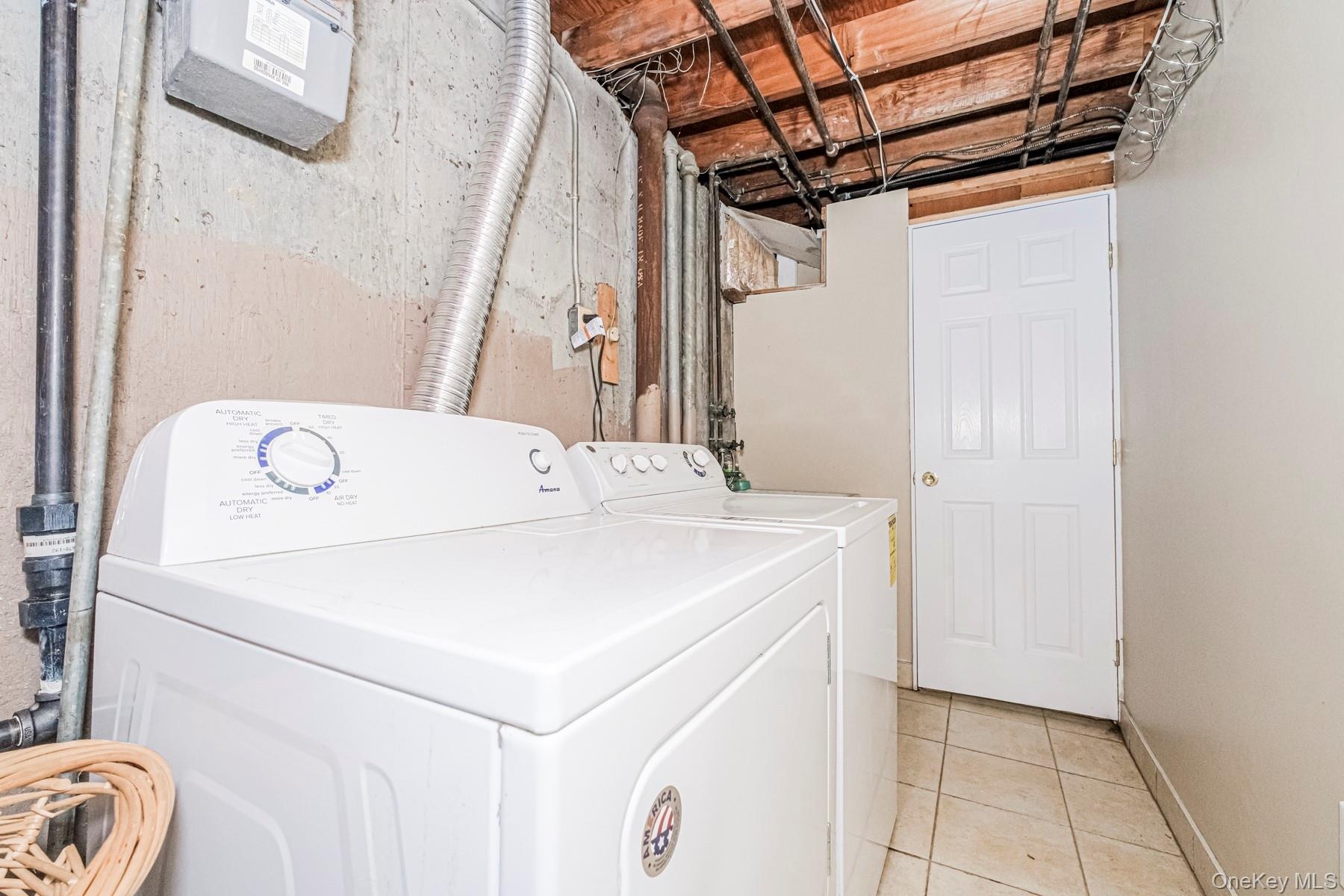 Dedicated laundry area featuring a tile floor, white appliances, and a paneled door