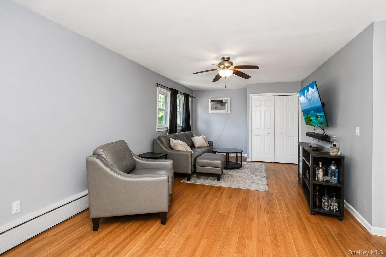 Living space featuring wood-finish flooring, light gray wall paint, and white baseboards