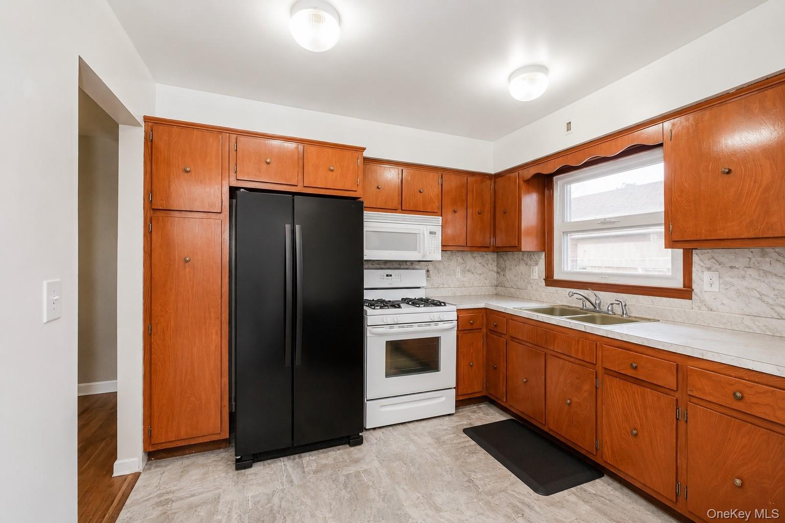 Kitchen featuring wood cabinetry, white countertops, a double-basin sink, and a window above