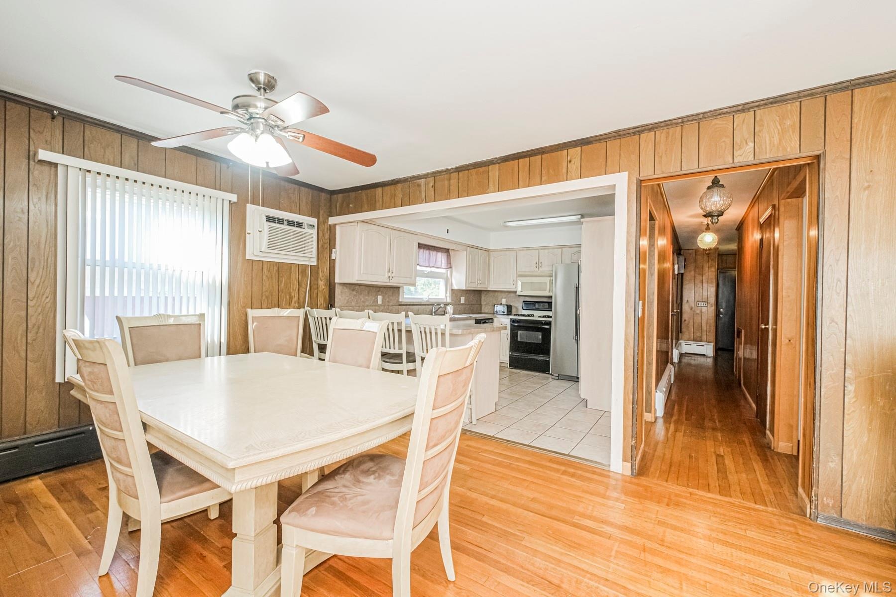 Hardwood flooring defines this dining space, featuring a ceiling fan with integrated lighting