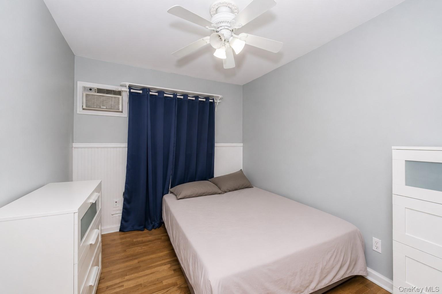 Room featuring light gray walls, white wainscoting, and wood-finish flooring
