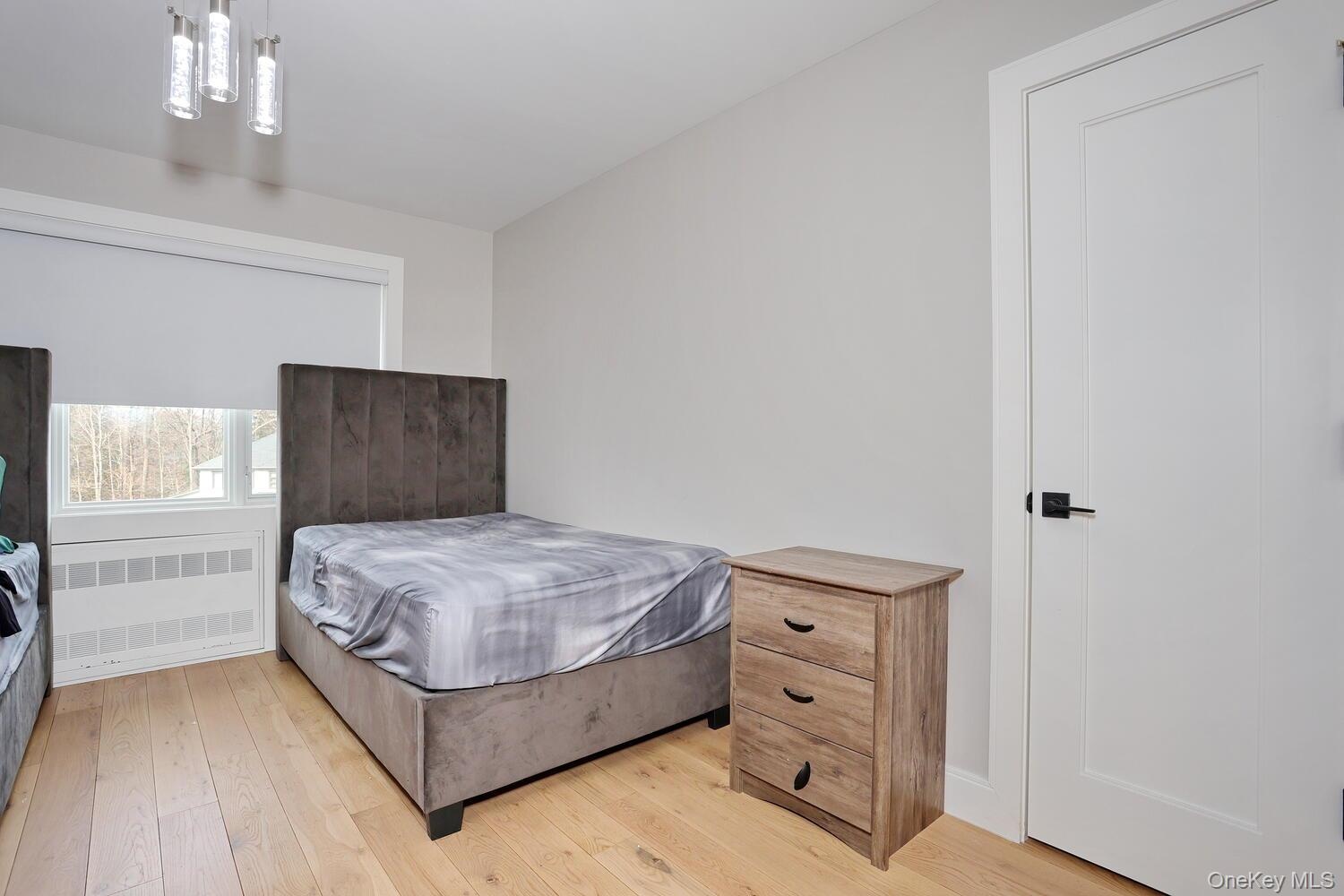 Bedroom with radiator and light wood finished floors