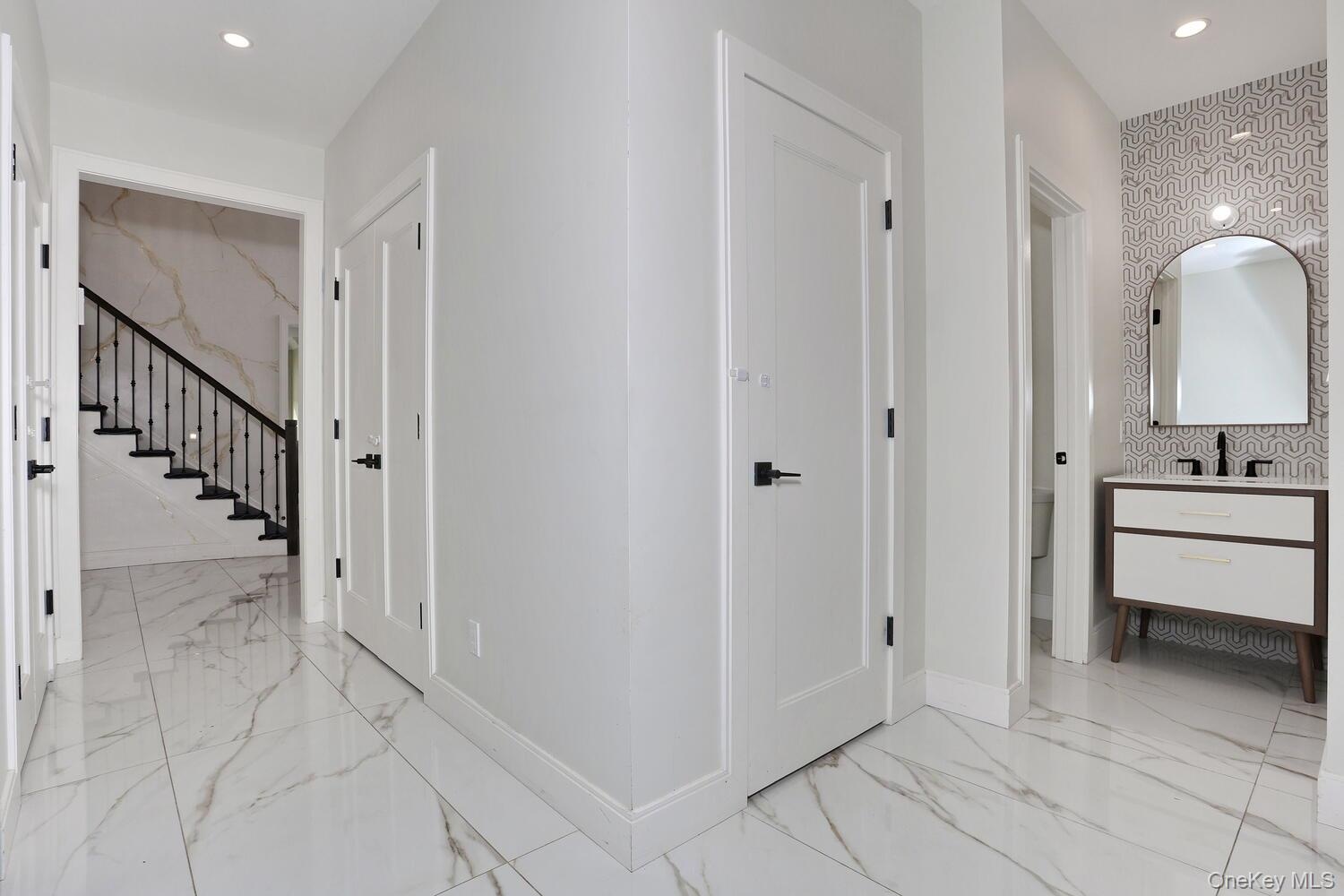 Corridor with recessed lighting, light marble finish flooring, and stairway
