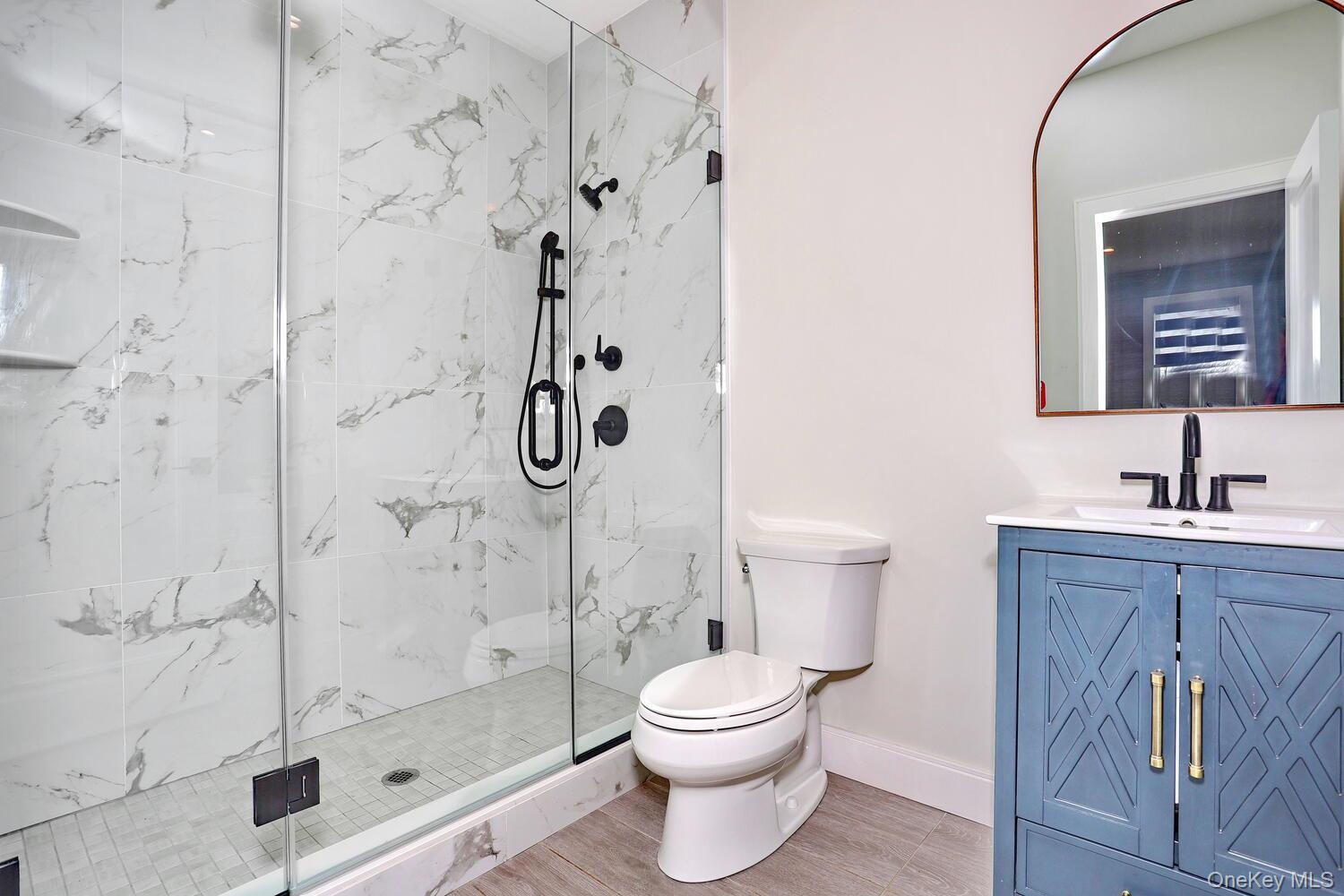 Full bath with vanity and a marble finish shower